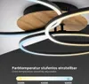 A close-up view of a modern ceiling lamp with swirling rings, showcasing its adjustable color temperature feature. Produktbild-Vorschau