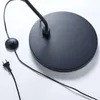 The base and power cord of a black floor lamp are shown against a white background. Produktbild-Vorschau