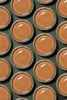 A top-down view of multiple open jars of hazelnut spread arranged in a grid pattern on a dark green background. Produktbild-Vorschau