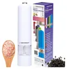 A white electric pepper grinder is shown next to a box displaying multiple colored grinders and text. A wooden spoon with pink salt and a pile of black peppercorns are also visible. Podgląd zdjęcia produktu