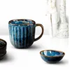 A close-up shot of a blue ceramic mug and a small bowl on a white surface. Produktbild-Vorschau