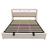 A beige upholstered bed frame with a slatted mattress support and LED lighting in the headboard, shown from the front. Náhled obrázku produktu