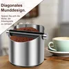 A coffee knock box filled with coffee grounds, with a cup of coffee in the background. Produktbild-Vorschau