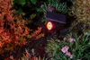 A solar-powered spotlight illuminates plants in a garden at night. Voir les images du produit