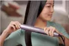 A woman is straightening her hair with a hair straightener. Voir les images du produit