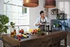 A woman is cooking in a kitchen, with various ingredients and cooking utensils on a wooden counter. Náhled obrázku produktu
