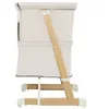 A side view of a beige and wood baby crib/bassinet. Produktbild-Vorschau