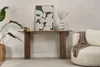A console table with a piece of art and a vase on it, next to a sofa with a throw blanket. Voir les images du produit