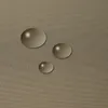 Three water droplets on a textured brown surface. Produktbild-Vorschau