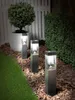 Three solar garden lights illuminate a pathway at night, with a manicured bush and a potted plant in the background. Produktbild-Vorschau