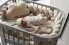 A newborn baby lying in a crib with a cloud-shaped pillow. Produktbild-Vorschau