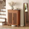 A wooden shoe cabinet with slatted doors and a drawer, placed near a staircase and a full-length mirror in a home entryway. Náhľad obrázku produktu