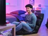 A young person is playing a video game in a bedroom with colorful lighting. Náhľad obrázku produktu