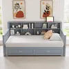 A gray wooden daybed with a built-in bookshelf headboard and two storage drawers underneath, set in a room with artwork on the wall and a window in the background. Anteprima dell’immagine prodotto