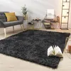 A living room scene featuring a dark gray shaggy rug, a gray armchair with a yellow cushion, and various decorative items on side tables and a shelf. Produktbild-Vorschau