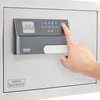 A hand is shown pressing a button on a digital keypad of a safe. Produktbild-Vorschau