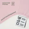 A close-up of a pink fabric with text and care symbols. Produktbild-Vorschau