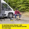 A man is cleaning his boots with a portable pressure washer next to a camper van. Náhled obrázku produktu