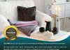 A cozy living room scene with a blanket and pillow on a sofa, decorated with candles and pinecones. Produktbild-Vorschau