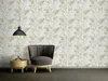 A chair and side table are placed in front of a patterned wallpaper. Produktbild-Vorschau
