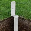 A metal post anchor is shown partially buried in the ground, with grass above. Produktbild-Vorschau