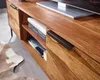A close-up view of a wooden TV stand with books on a shelf and a drawer handle. Produktbild-Vorschau