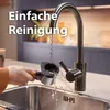 A person is rinsing a coffee machine portafilter under a faucet in a kitchen sink. Voir les images du produit
