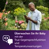 A man is looking at his phone in a garden with flowers. Produktbild-Vorschau
