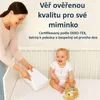 A woman is placing a white sheet into a crib where a baby is sitting. Náhled obrázku produktu