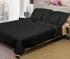 A black comforter set with gold trim is laid out on a bed. Podgląd zdjęcia produktu