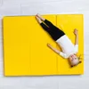 A young girl is lying on a yellow gymnastics mat. Voir les images du produit