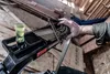 A person's hand is holding a triangular measuring tool over a black tool with nails in it. Anteprima dell’immagine prodotto