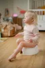 A young child sits on a potty in a nursery. Produktbild-Vorschau
