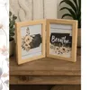 Two wooden photo frames with floral and text inserts are displayed on a wooden surface, with a knitted blanket and a plant in the background. Produktbild-Vorschau