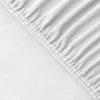 A close-up view of a white fitted sheet with elastic gathering along the edge. Produktbild-Vorschau