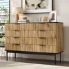 A wooden dresser with black legs and a black top is placed in a room with a window and some decor on top. Produktbild-Vorschau
