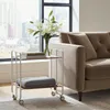 A rolling cart with books and a blanket next to a sofa in a room with a city view. Voir les images du produit