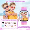 Two children wearing sunglasses are posing on a beach, with a smartwatch displayed prominently on the right side of the image. The smartwatch screen shows a selfie of the children. There are also decorative icons related to emoticons and masks displayed. Náhled obrázku produktu