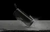 A black Sony Bluetooth speaker is shown tilted on a textured gray surface, with water splashing around it against a black background. Voir les images du produit