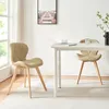 Two beige dining chairs are placed around a white dining table in a well-lit room. Produktbild-Vorschau