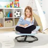 A young girl sits on a blue swivel chair, reading a book in a child's playroom. Produktbild-Vorschau