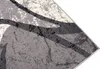 A close-up view of a rug with a modern abstract pattern in shades of gray, cream, and black. Produktbild-Vorschau