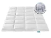A white quilted duvet is laid out flat on a white background. A circular overlay shows a snowy path lined with trees. Voir les images du produit
