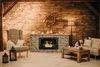 A cozy living room scene with a fireplace, armchair, and sofa, decorated for the holidays. Anteprima dell’immagine prodotto