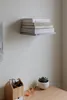 A stack of books on a floating shelf mounted on a white wall above a wooden desk with a desk organizer and a potted succulent. Anteprima dell’immagine prodotto