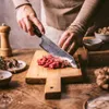 A person is chopping minced meat on a wooden cutting board. Podgląd zdjęcia produktu