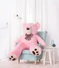A large pink teddy bear is sitting on a light blue armchair in a room with white curtains. Podgląd zdjęcia produktu