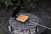 A sandwich maker is being used to toast a sandwich over hot coals on a grill. Anteprima dell’immagine prodotto