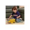 A young boy is playing with a yellow toy bus and a small figure on the floor next to a couch. Anteprima dell’immagine prodotto