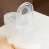 A clear plastic storage container with its lid open, placed on a white surface with a blurred brown background. Anteprima dell’immagine prodotto